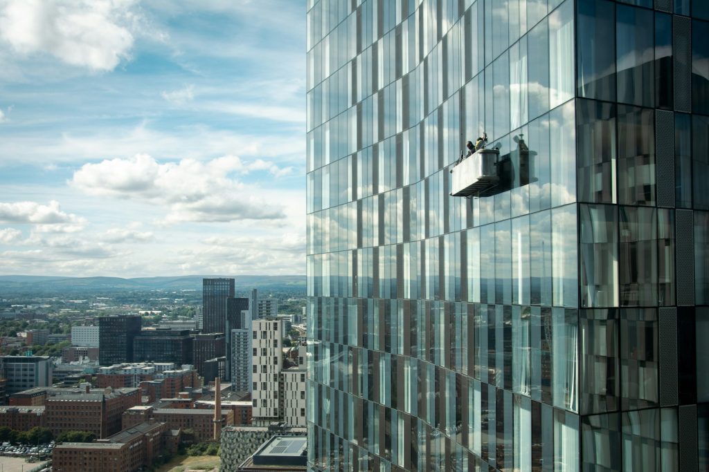 Zeitclean Professionelle Gebäudereinigung in München und Berlin : Arbeiter reinigen die Fenster eines hohen Bürogebäudes und sorgen für makellose Sauberkeit, Hygiene und professionelle Reinigungslösungen in der gesamten Immobilie.